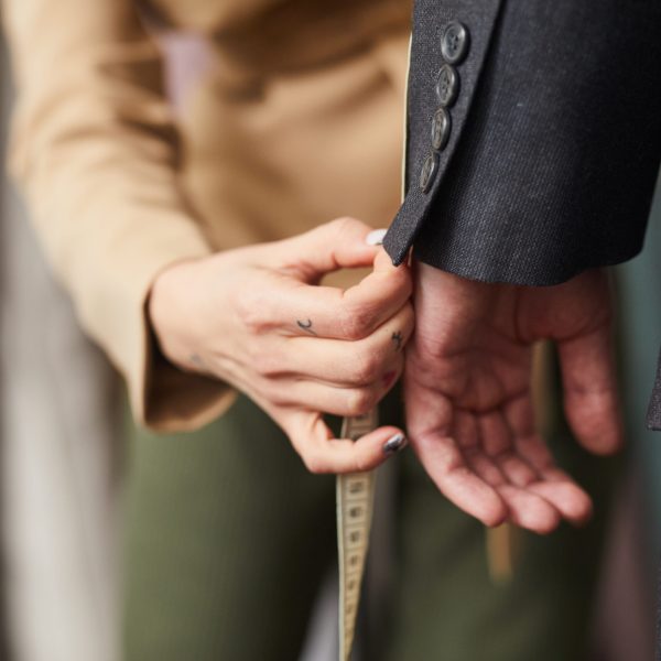 Close-up of tailor measuring the sleeve of suit with tape measure